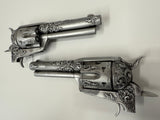 Two ornate silver revolvers on a light gray background